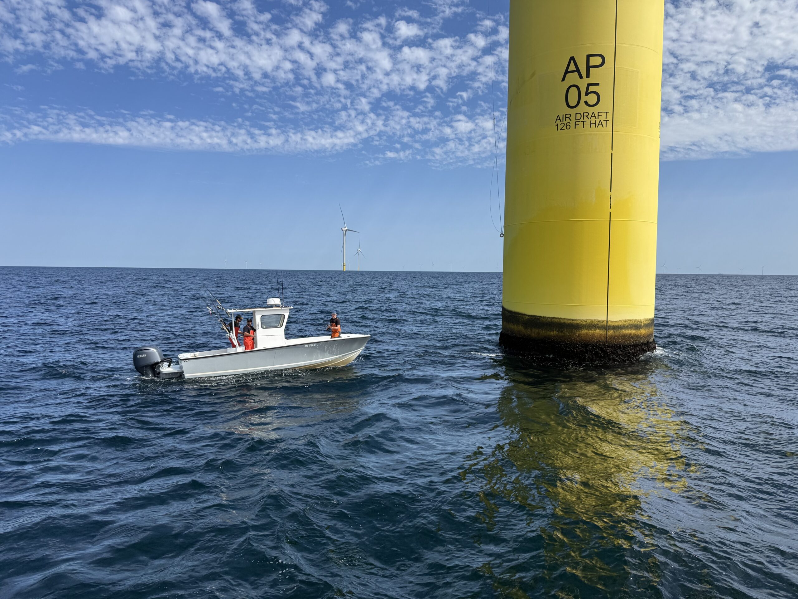 Small boat pulled up close to a turbine base, showing open access